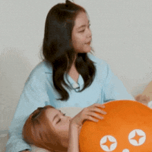 two women are laying on a couch one is holding an orange pillow with a star on it