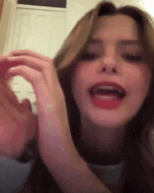 a close up of a woman 's face with her mouth open and her hands on her hair .