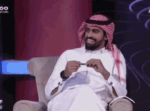a man with a beard is sitting in a chair holding a piece of paper