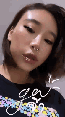 a woman with a nose ring is wearing a black shirt with flowers on it and is looking at the camera .