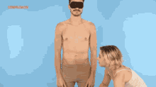 a man wearing a blindfold is being kissed by a woman in front of a blue background with cosmopolitan.com written on it