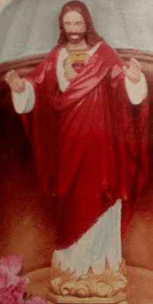 a statue of jesus wearing a red robe and white sleeves