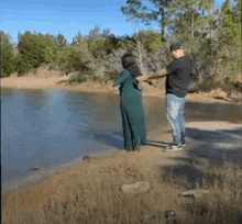 a man is standing next to a woman in a green dress who is floating in the water .