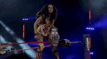 a female wrestler is standing in a wrestling ring holding a belt .