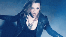 a woman wearing a black leather jacket is making a silly face