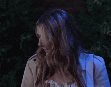 a woman is laughing with her mouth open in front of a tree .