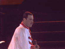a man with a mustache is singing into a microphone while holding a white cloth .