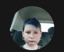 a young boy with blue hair is sitting in a car seat .