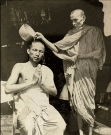 a man is being poured water on his head by another man