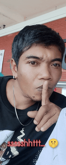 a man holds his finger to his mouth with the words sssshhtt behind him