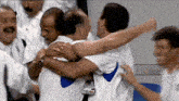 a group of men are hugging each other while wearing white shirts .