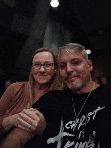 a man and a woman are posing for a picture and the man is wearing a shirt that says christ is king