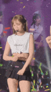 a woman wearing a lesseraf shirt is dancing on stage