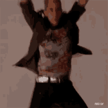 a blurry picture of a man wearing a black jacket and a t-shirt is walking .