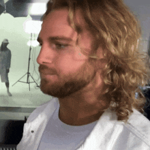 a man with long blonde hair and a beard is wearing a white jacket