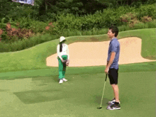 a man and a woman are playing golf on a green and the man is holding a golf club