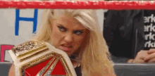 a woman is holding a wrestling championship belt and making a face .