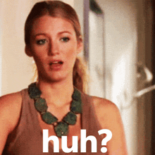 a woman wearing a necklace and a tank top is asking the question huh