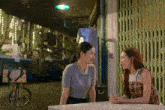 two women are sitting at a table and talking to each other