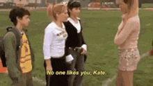 a group of girls are standing on a field and one of them is talking to another girl .