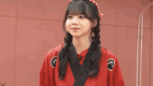 a young woman wearing a red shirt and a red headband is making a face .