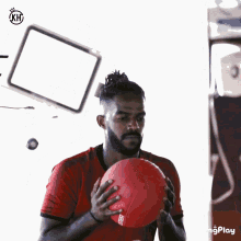 a man in a red shirt holds a red ball in his hands
