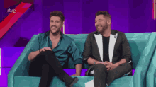 two men are sitting on a couch with rtve written on the screen