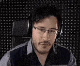 a man wearing headphones is sitting in a chair with his mouth open and making a funny face .
