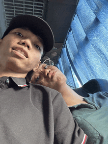 a man wearing a hat and glasses laying on a woman 's lap