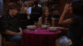 a group of people are sitting at a table with bowls of food and drinks