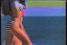 a woman in a bikini is taking a picture of the ocean with a camera