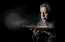 a man with glasses is reading a book in the dark
