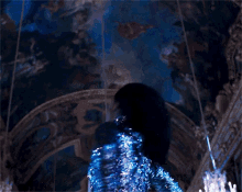 a dark room with a painting on the ceiling and a person in a blue costume