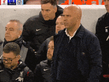 a group of men are watching a soccer game with the score 1-0
