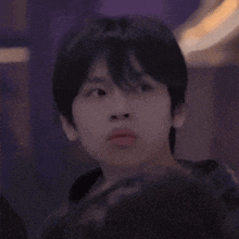 a young boy with black hair is making a funny face while looking at the camera .