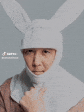 a man is wearing a white bunny hat and scarf around his neck .