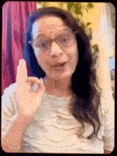 a woman wearing glasses and a white shirt is giving a middle finger