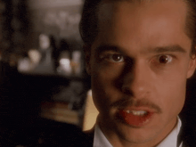 a man with a mustache is making a funny face with his tongue sticking out .