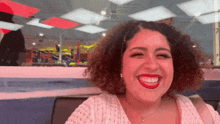 a woman with curly hair is smiling with red lipstick on her lips
