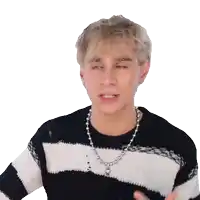 a young man wearing a black and white striped sweater and a silver chain around his neck