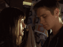 a man and a woman are looking at each other with a patterned curtain in the background