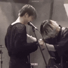 a man is singing into a microphone next to another man