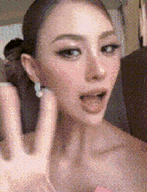 a close up of a woman 's face with her mouth open and a hand in front of her face .
