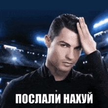 a man in a black jacket holds his hand to his forehead in front of a blue background with russian writing on it ..