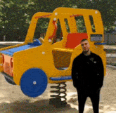 a man is standing in front of a yellow toy truck