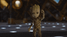 a baby groot from guardians of the galaxy is waving at the camera