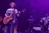 a blurry photo of a man playing a guitar on stage