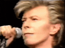 a close up of a man singing into a microphone in a dark room .