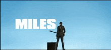 a poster for miles kane shows a man holding a guitar in front of a blue sky
