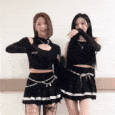 two women are standing next to each other wearing black clothes and stockings .